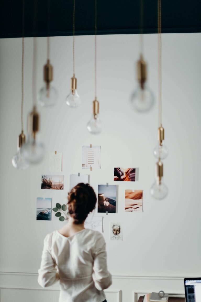 A woman looks at pictures hanging on the wall.