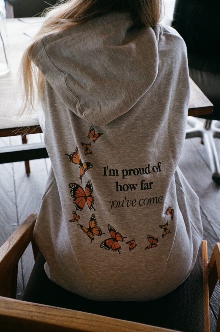 A woman wearing a hoodie that says "I'm proud of how far you've come".