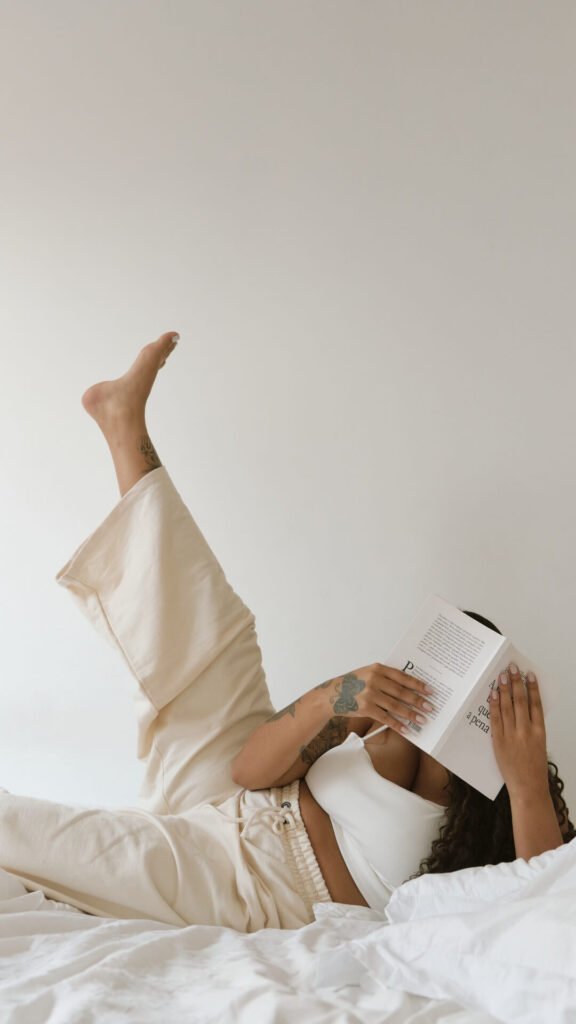 a woman lying in bed, reading a book.